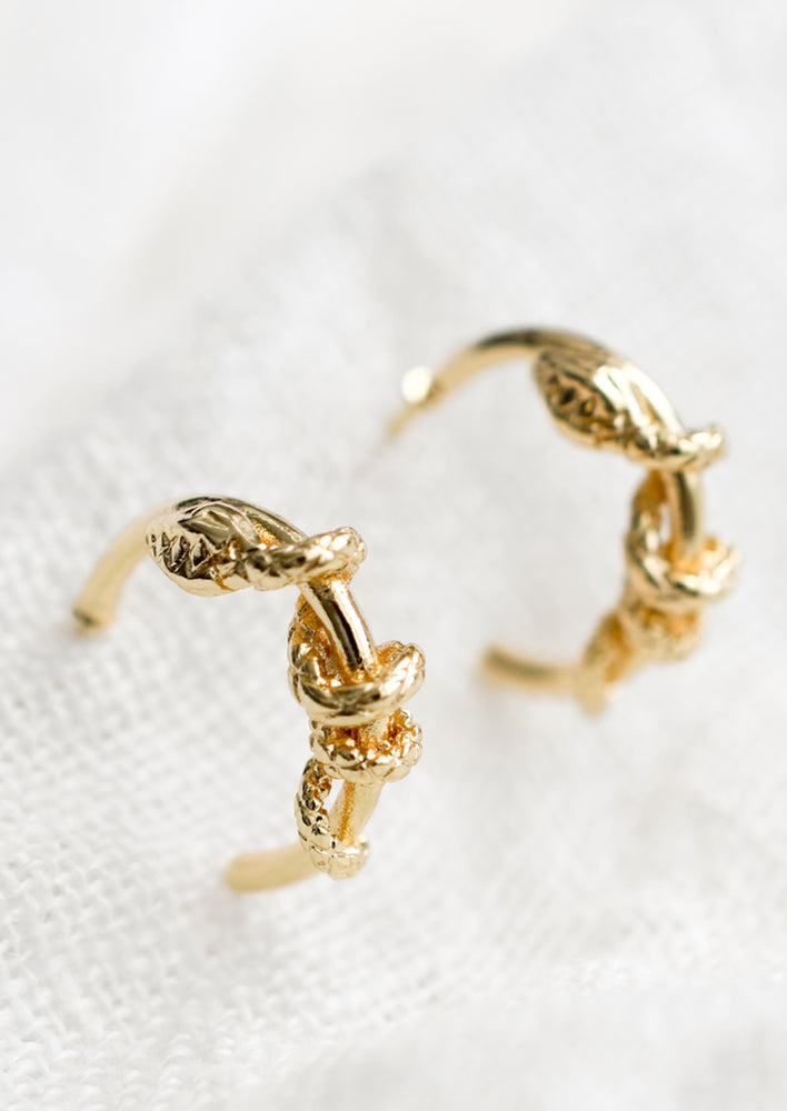 A pair of gold hoop earrings with snake coiled around them.