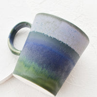 Denim / Moss: A ceramic coffee mug with handle in mottled blue and green glaze.
