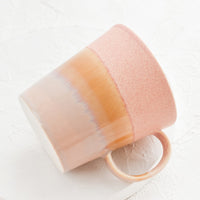 Pink / Beige: A coffee mug with a handle in pink, yellow and brown.