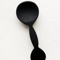Teaspoon: A carved black wooden teaspoon with decorative circular handle.
