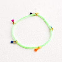 Mint Chip: Bracelet featuring green beads interspersed with 5 small multicolor string tassels on an elastic cord.