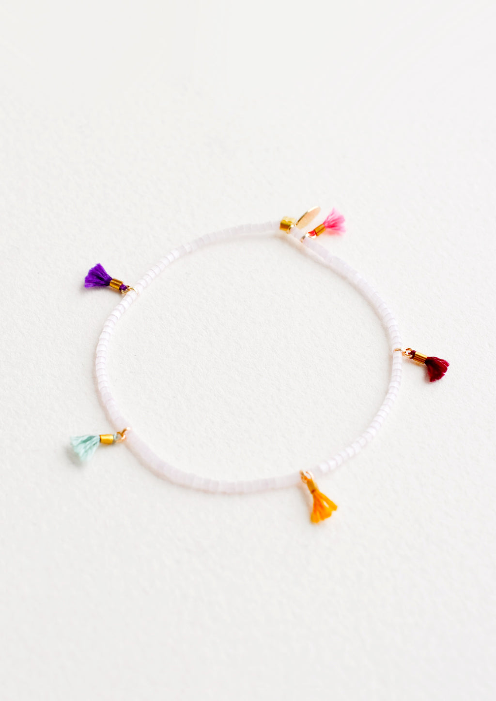 Rose Ice: Bracelet featuring white beads interspersed with 5 small multicolor string tassels on an elastic cord.