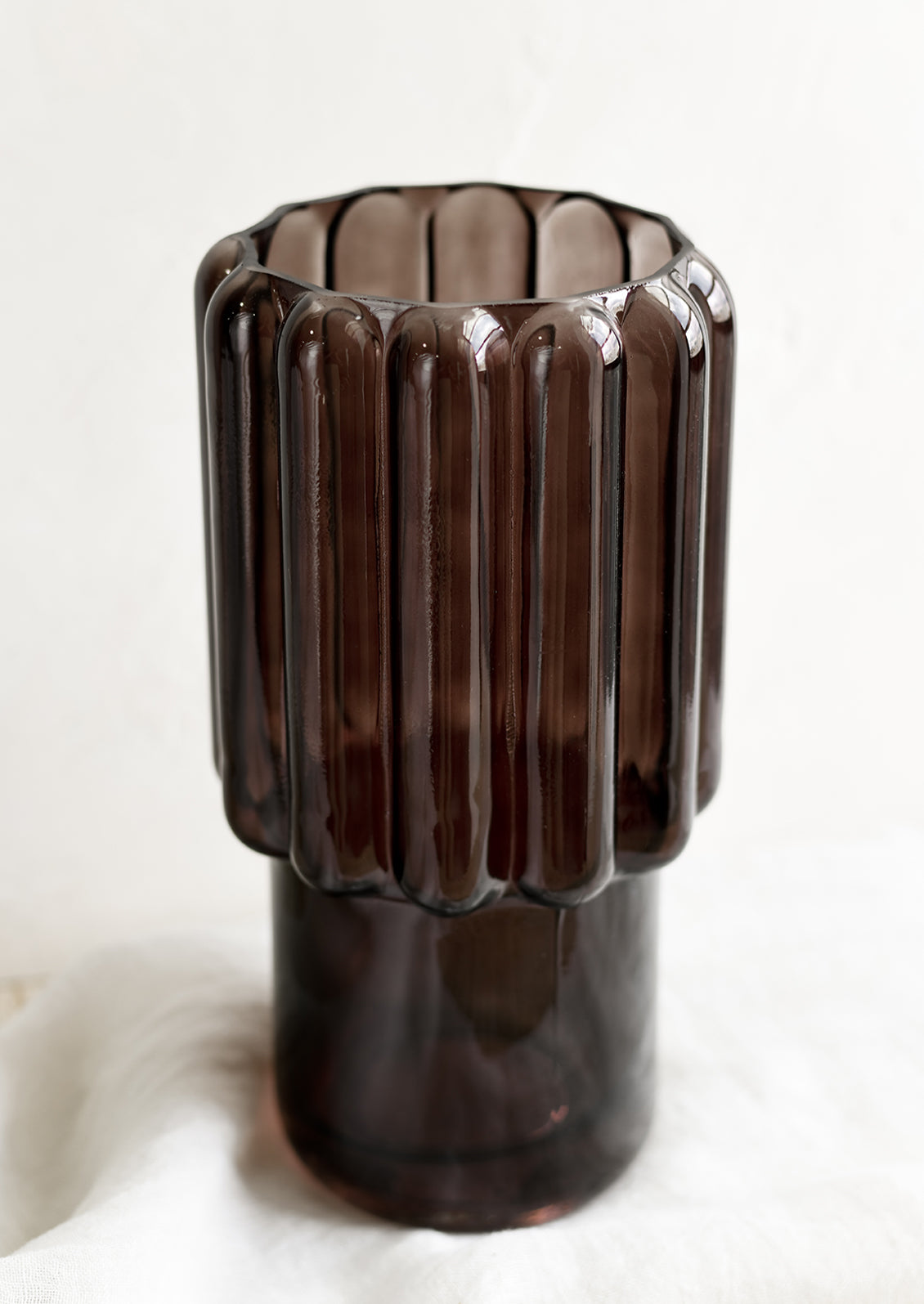 A large glass vase in dark brown with fluted texture.