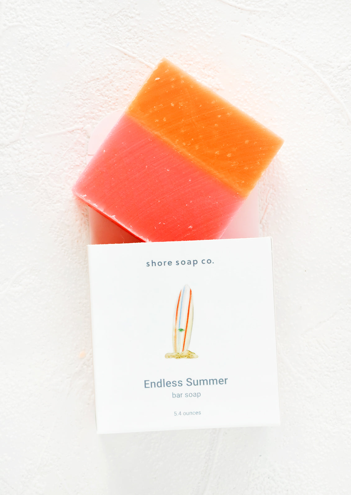 Square bar soap in pink & orange emerging from nautical themed packaging