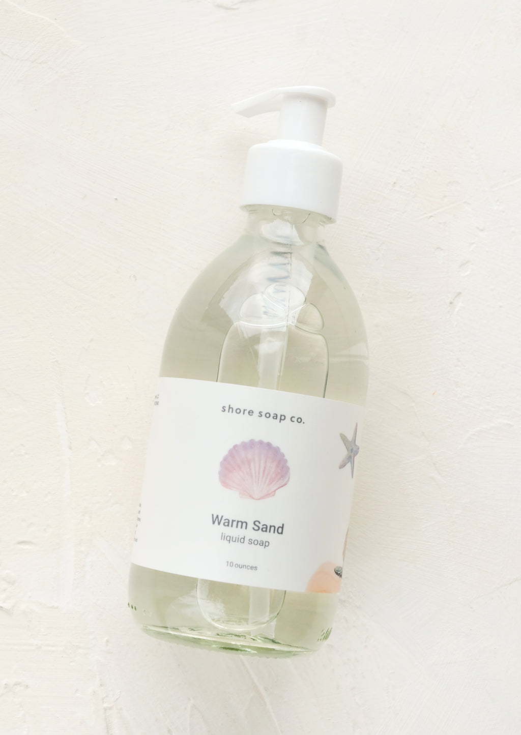 Warm Sand: A glass pump bottle containing liquid soap in "Warm sand" scent.