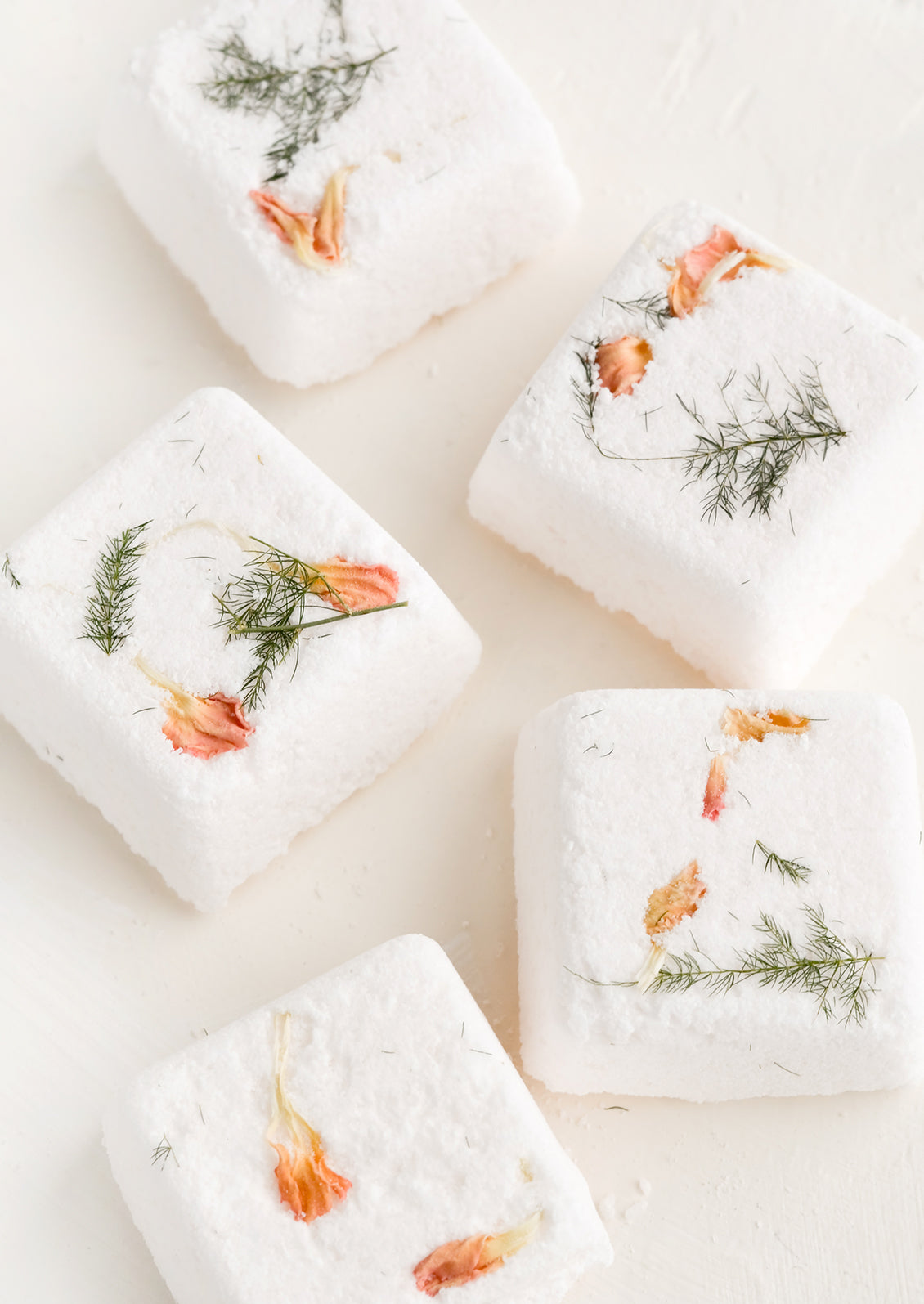 Square shower steamer tablets with embedded petals and leaves.