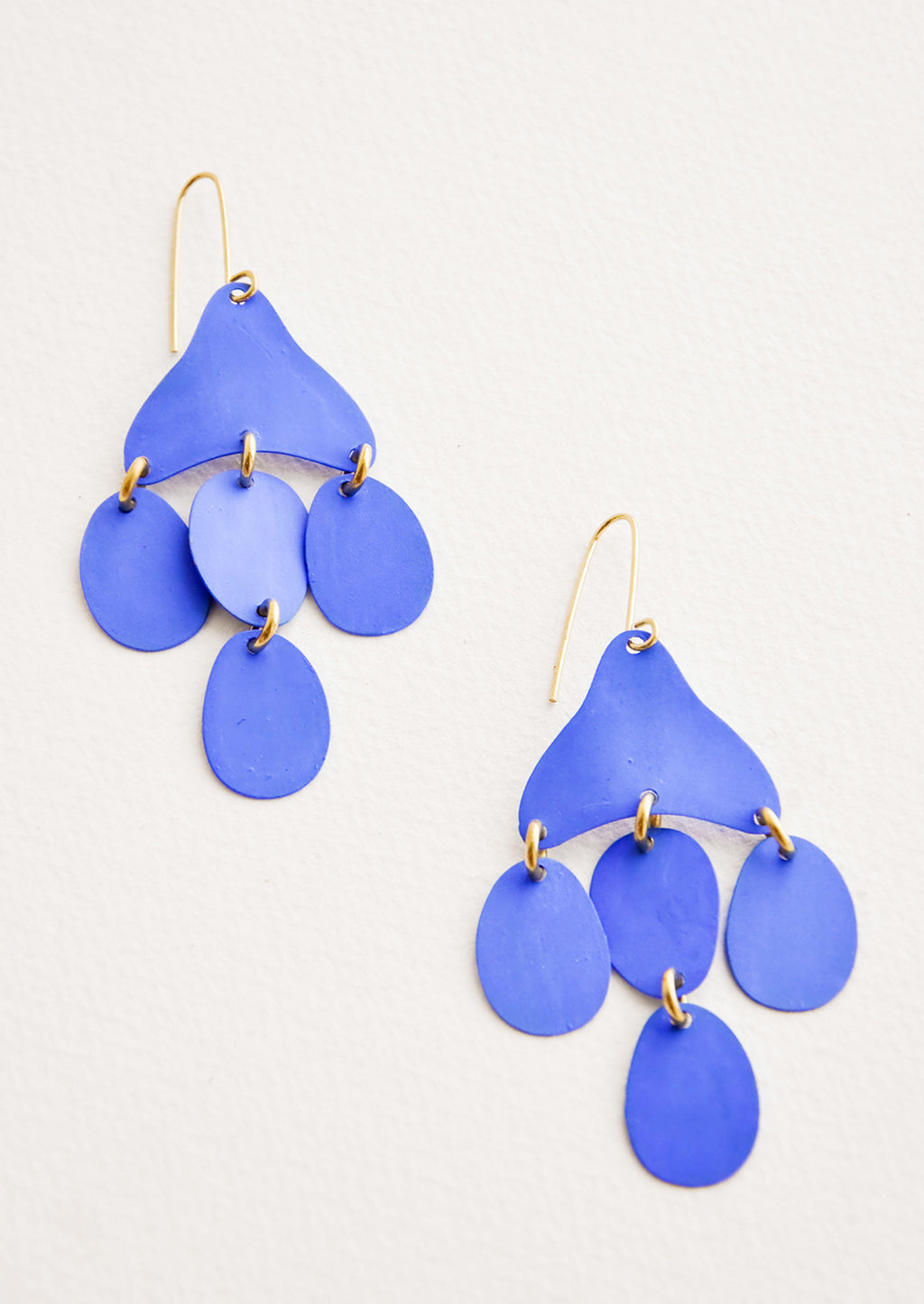 Cielo: Dangling earrings featuring 4 oval shape charms in matte bright blue metal hanging from an asymmetric triangle in the same color.