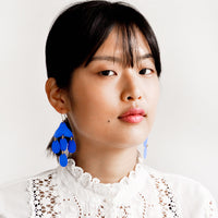 3: Model shot showing woman wearing earrings and a white top.