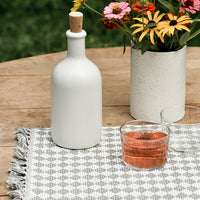 2: A placemat on table with white bottle and vase of flowers.