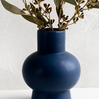 2: A navy blue sculptural ceramic vase with dried eucalyptus.