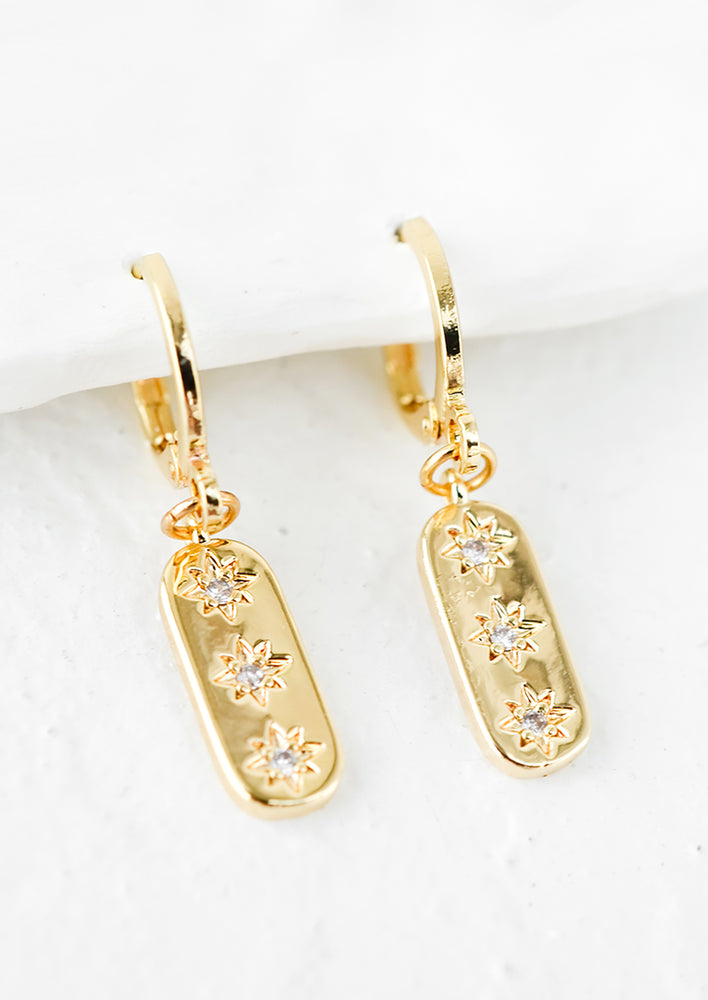 A pair of oval shaped gold earrings with star crystal detailing.