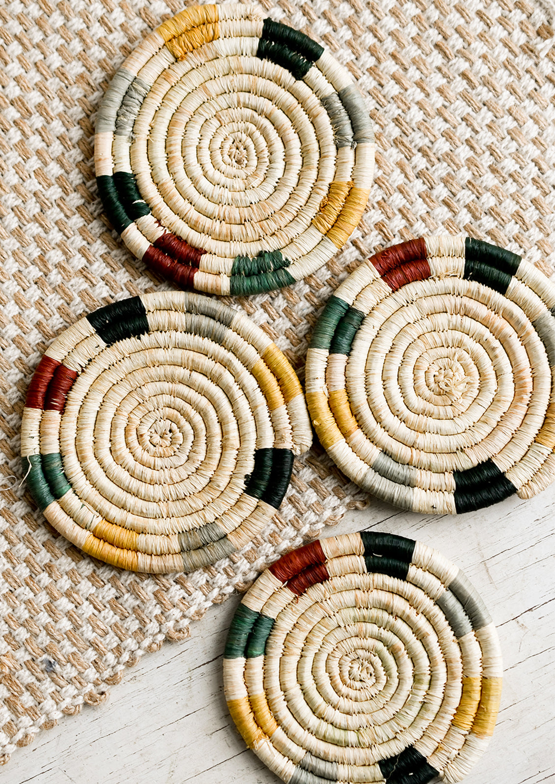 A set of natural raffia coasters with muted primary hue trim detail.