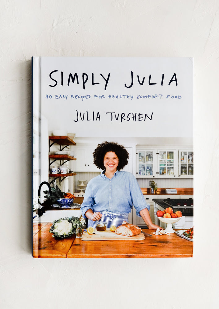 A hardcover cookbook with a woman in a kitchen on the cover.