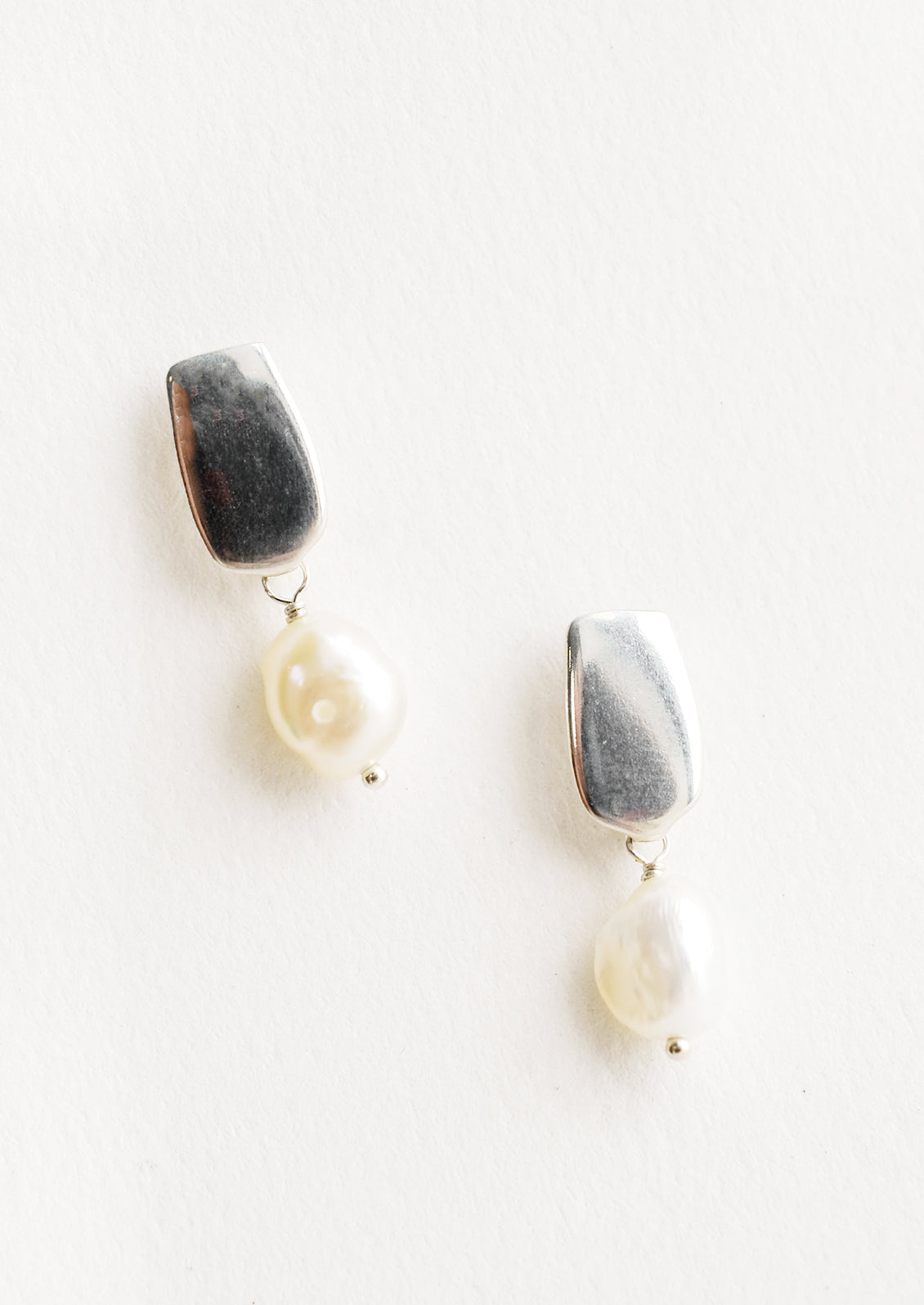 Earrings with a rectangular silver post and small pearl drop.