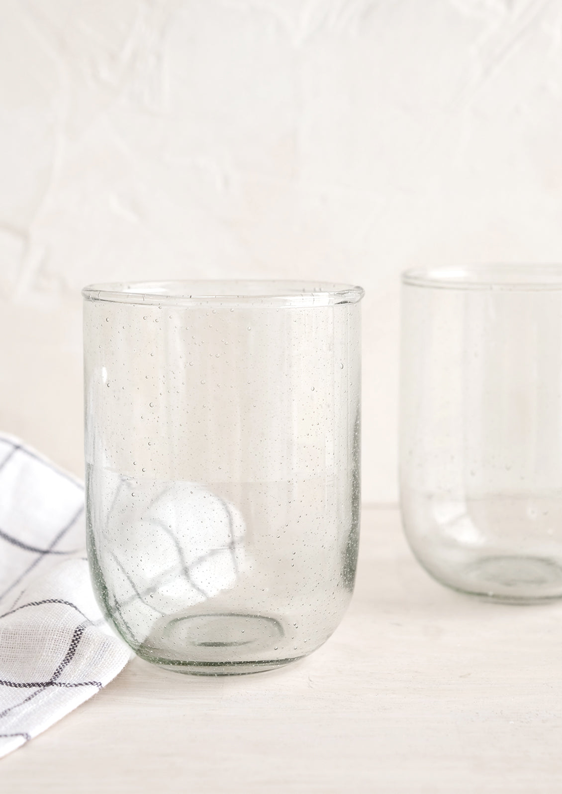 Short glass tumblers in clear recycled glass.