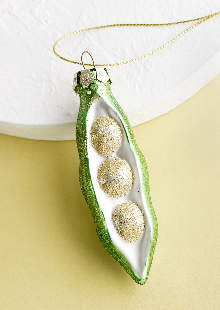 A decorative glass ornament in the shape of a sugar snap pea.