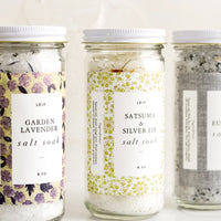 6: Three glass jars with decorative labels containing bath salt soaks.
