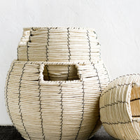 1: A round belly shaped basket in natural cord with thin black vertical stripe.