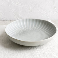2: A round ceramic pasta bowl with fluted texture.
