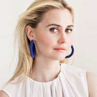 2: Model wears blue beaded hoop earrings and white blouse.