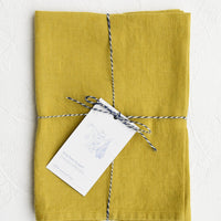 Chartreuse: A folded chartreuse linen tea towel tied in baker's twine with a decorative hangtag