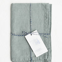 Lake Blue: A folded faded pale blue linen tea towel tied in baker's twine with a decorative hangtag