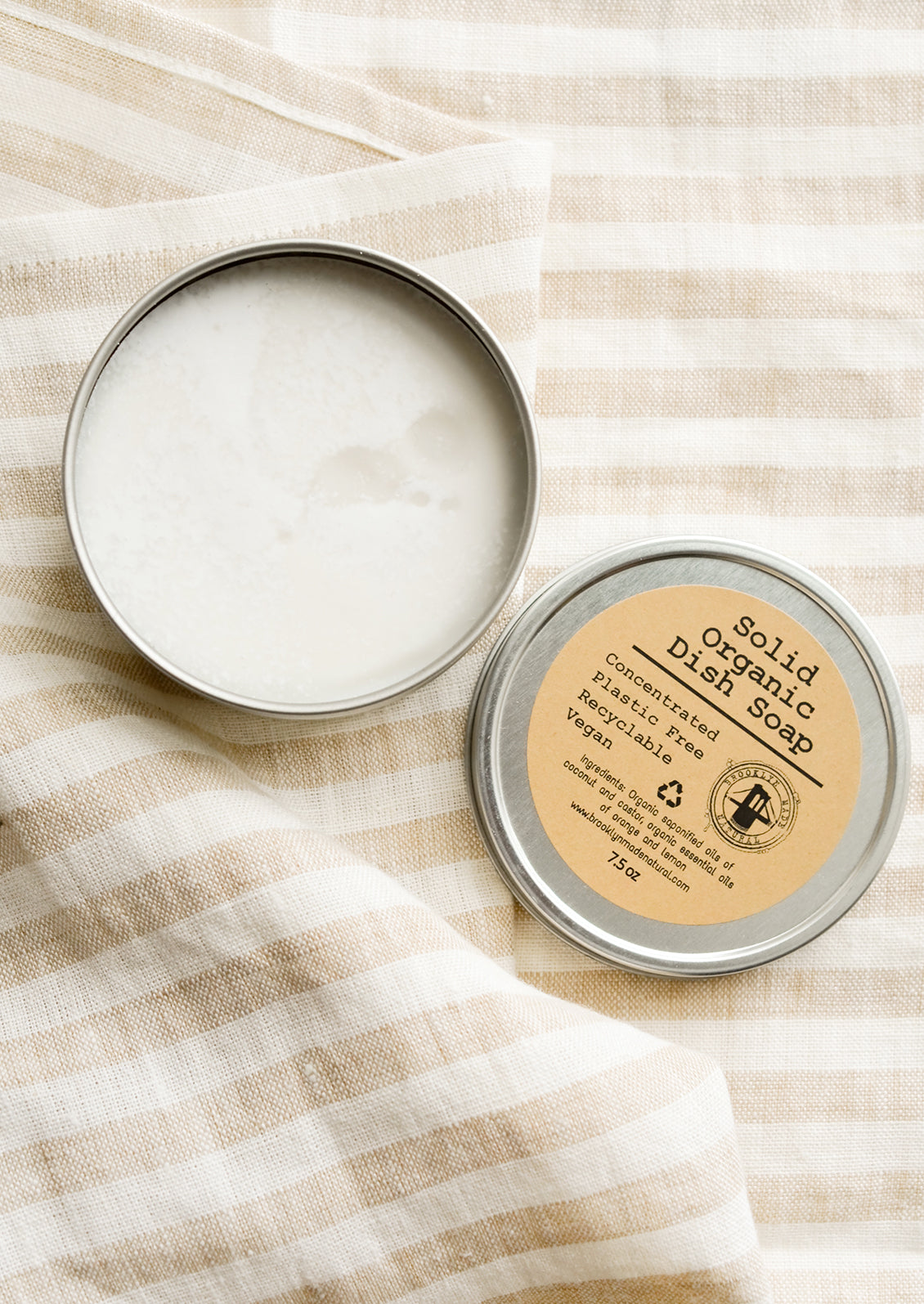 A metal tin containing solid dish soap.