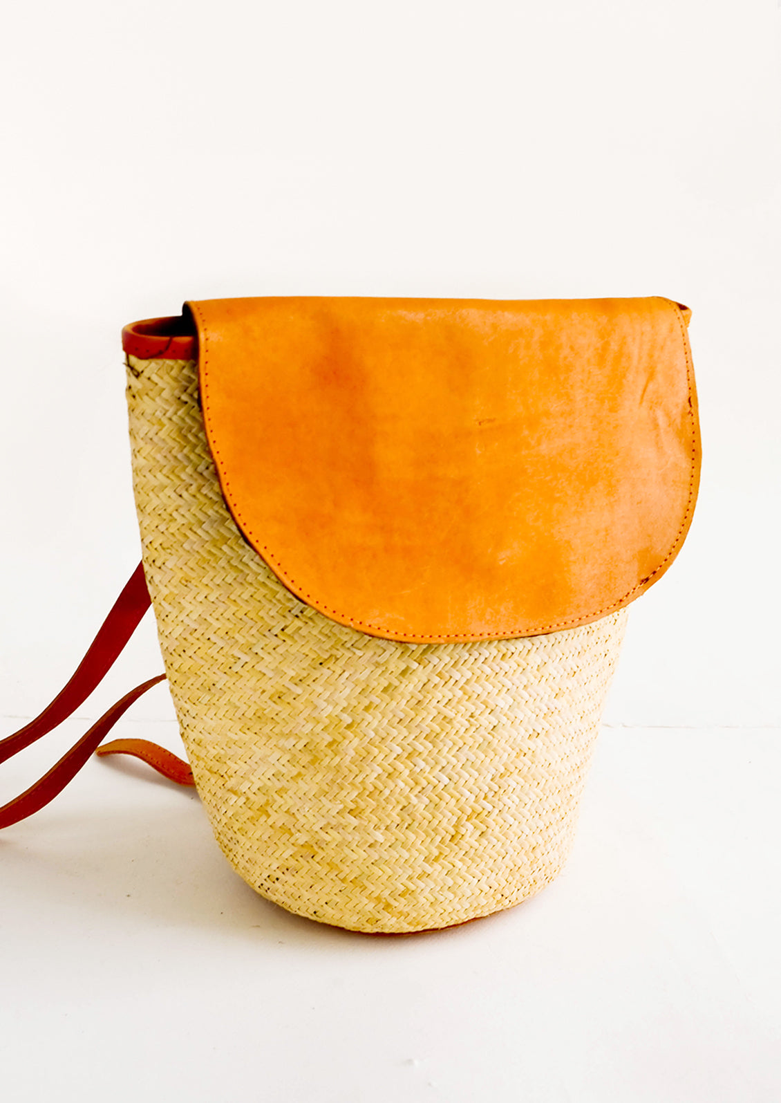 Woven straw backpack with leather trim and curved front flap