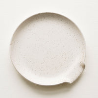 Natural: Circular ceramic spoon rest in ivory with tiny black speckles
