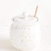 1: Round ceramic honey jar in speckled white glaze with fixed slot in lid for dipper