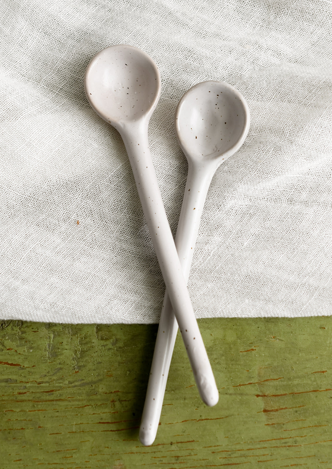 A stoneware spoon in white with dark speckles.