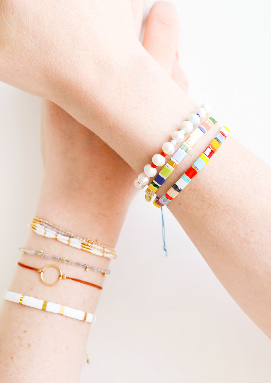 Model shot showing wrists with multiple styles of bracelets.