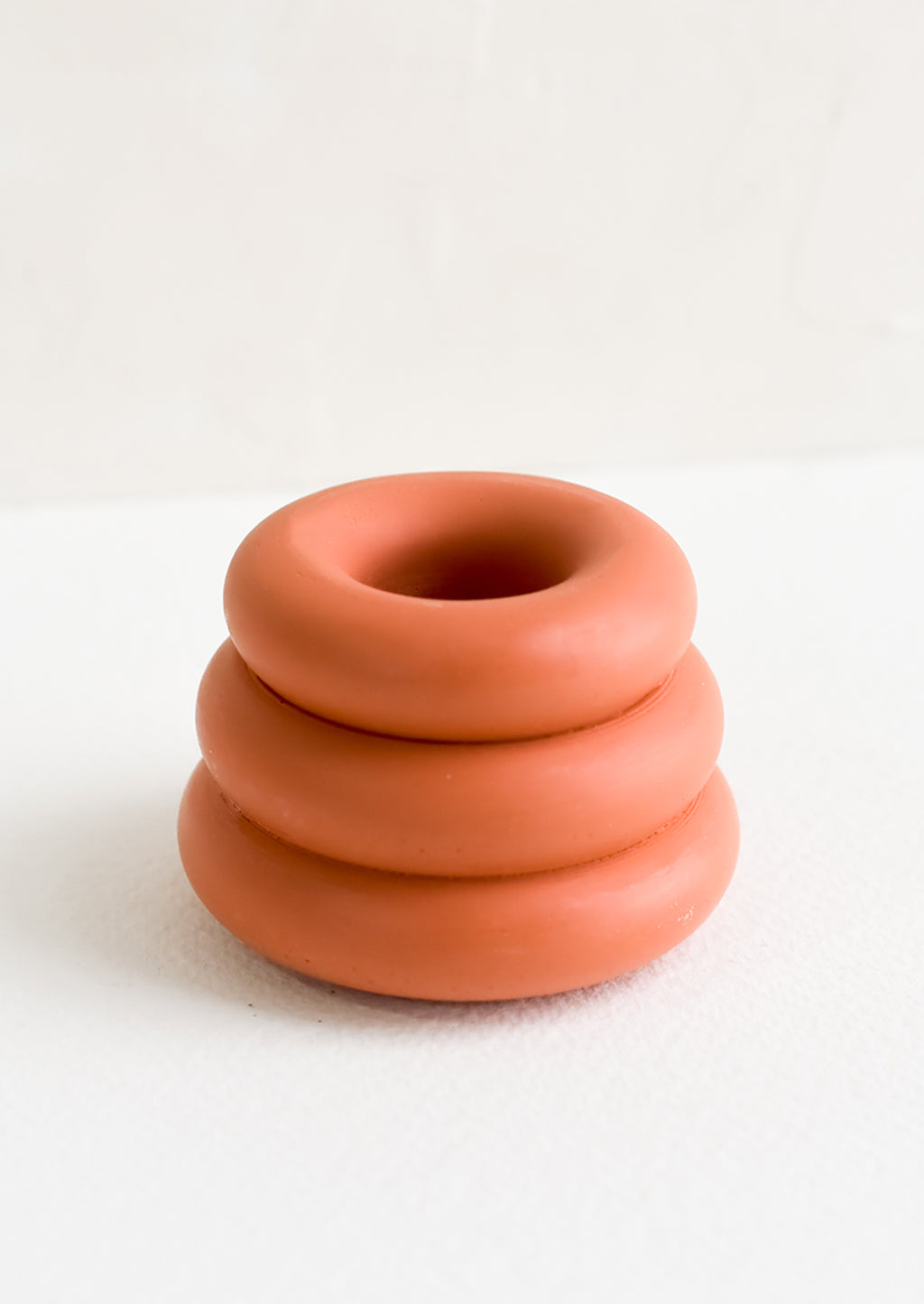Terracotta: A taper candle holder with 3-layer stacked donut shape in terracotta.