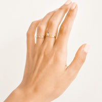 2: Woman's hand with rings on her ring and middle fingers.
