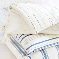3: A stack of pillows and blankets in blue, white and cream colors.