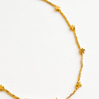 2: Close up shot of short necklace featuring round yellow gold beads interspersed with gold star beads and an adjustable closure.