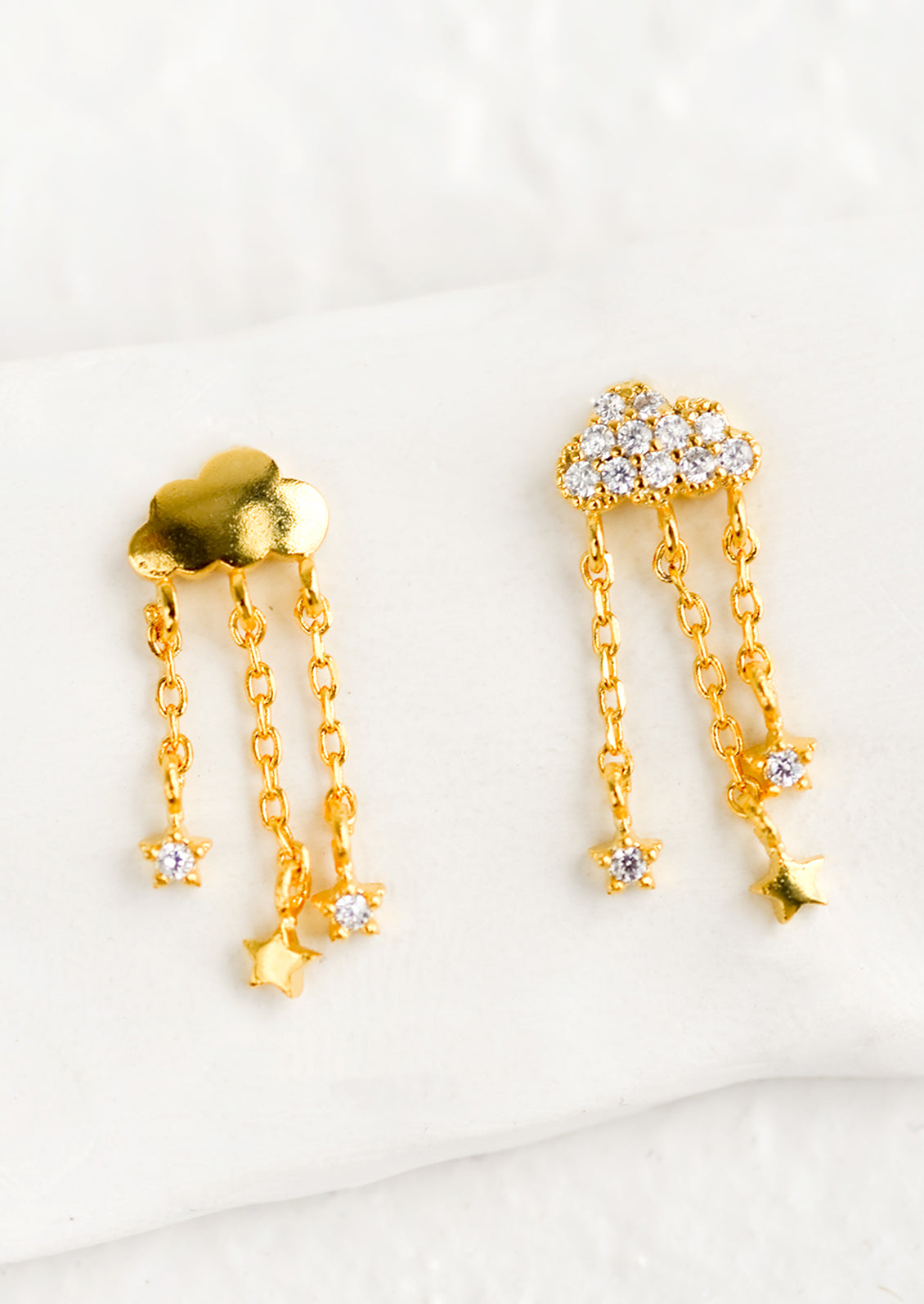 A pair of cloud shaped stud earrings, one crystal one plain, with chainlink "rain".