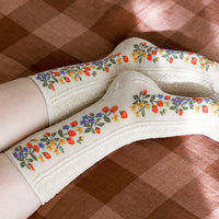 2: A pair of oatmeal colored socks with primary color strawberry print.