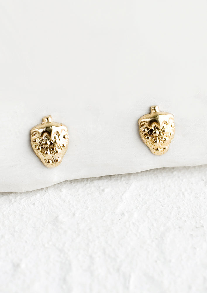 1: A pair of small gold stud earrings in the shape of strawberries.