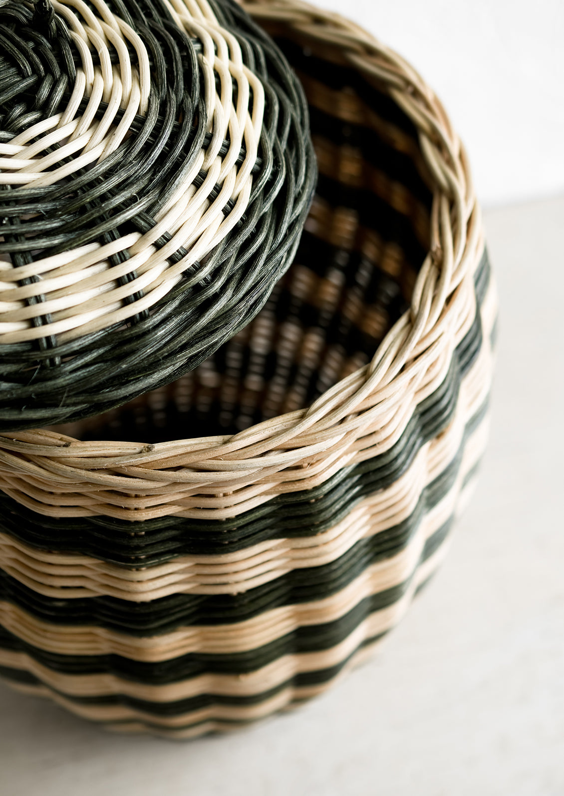 A tall hive shaped lidded basket in natural and dark green stripes.
