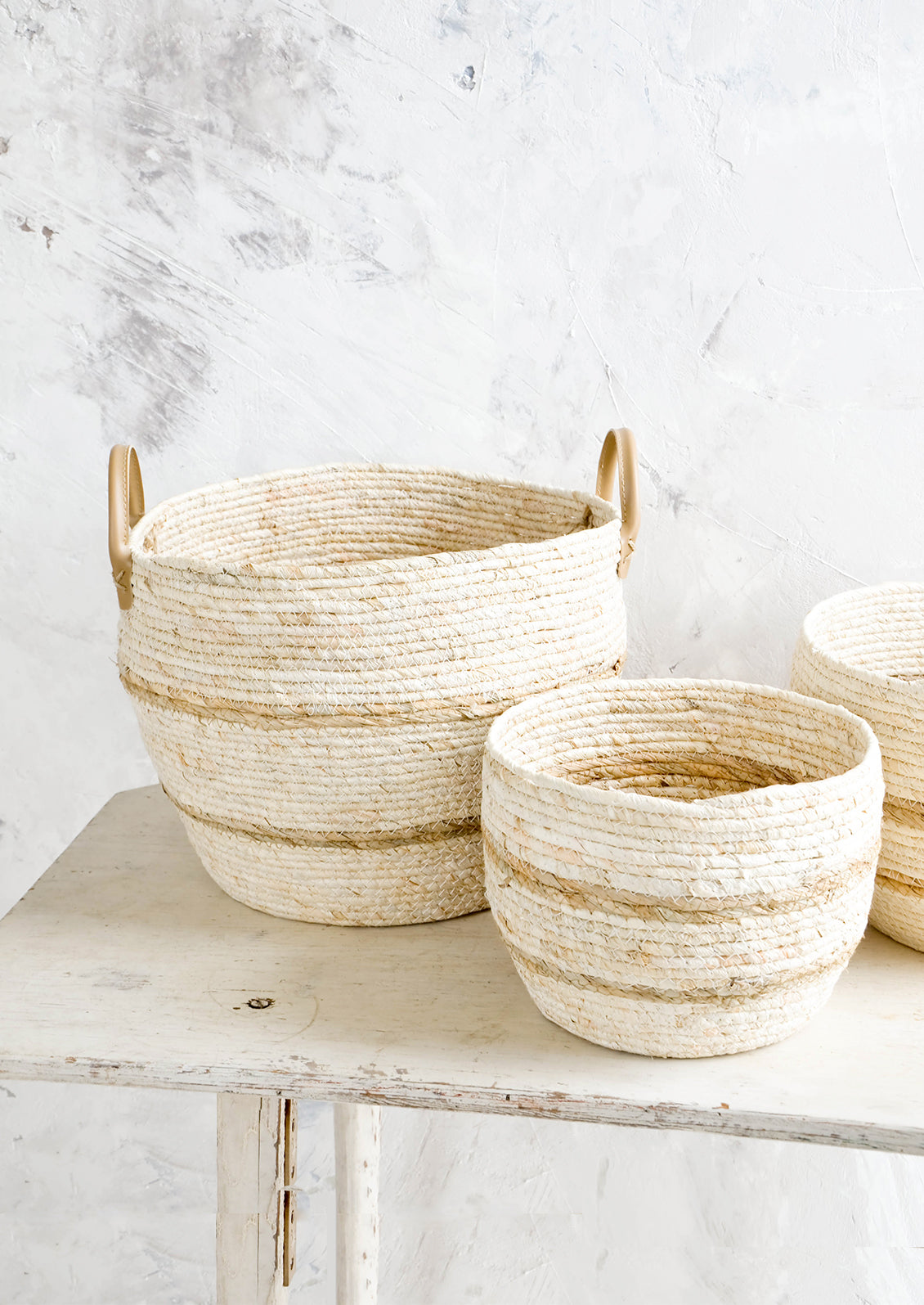 Round woven storage baskets in natural color, shown in three incremental sizes