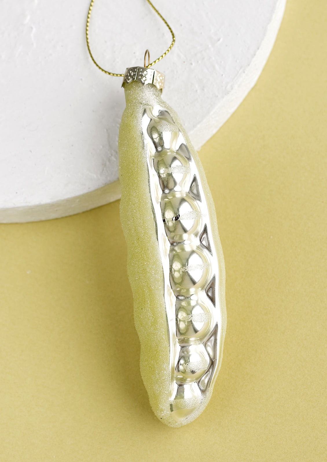 A glass holiday ornament of a sugar snap pea.