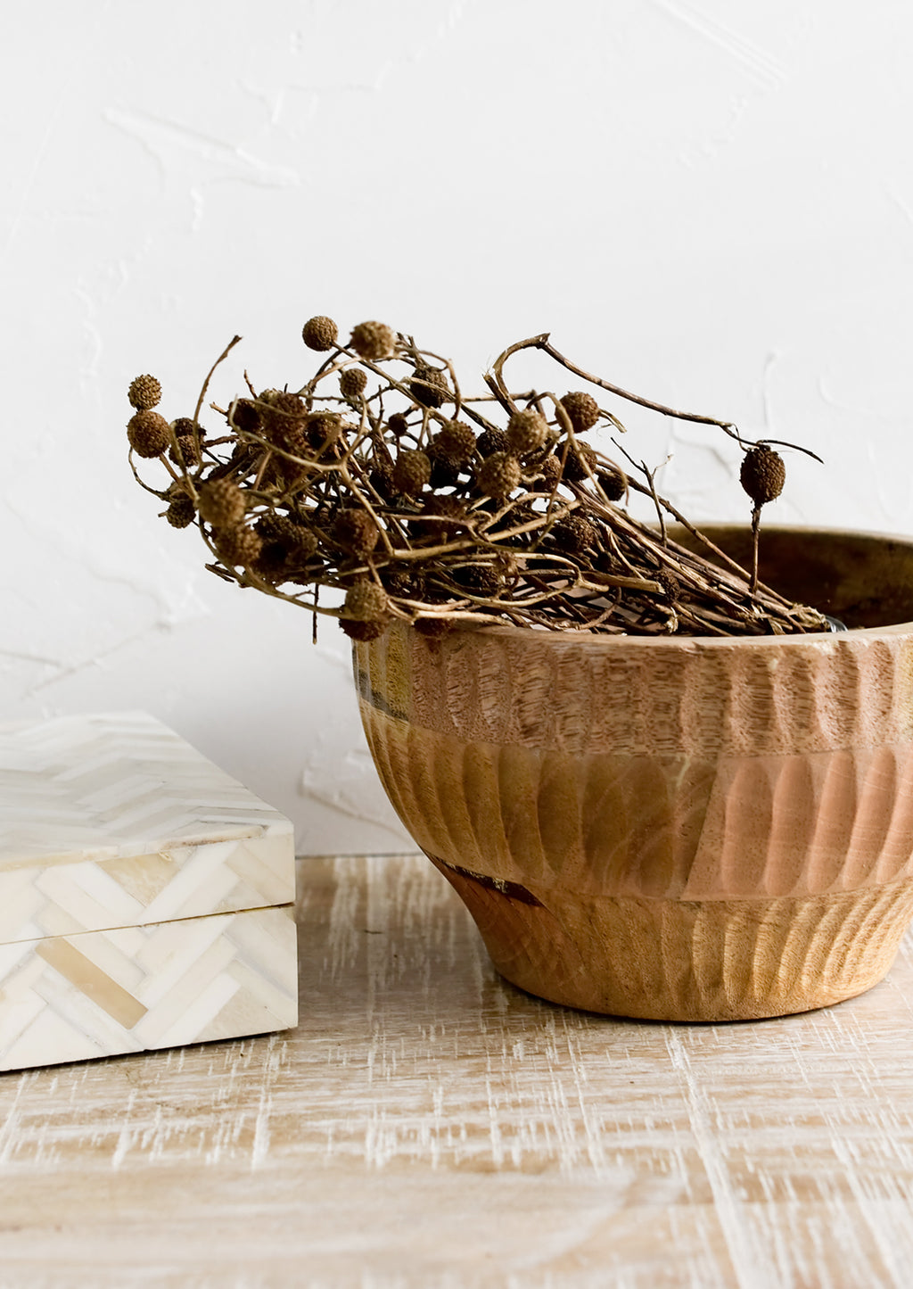 Medium: A wooden bowl housing dried seedpod bundle.