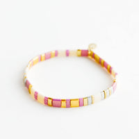 Lavender Cream: Bracelet featuring flat multicolor purple and cream glass beads interspersed with flat gold bead on an elastic cord.