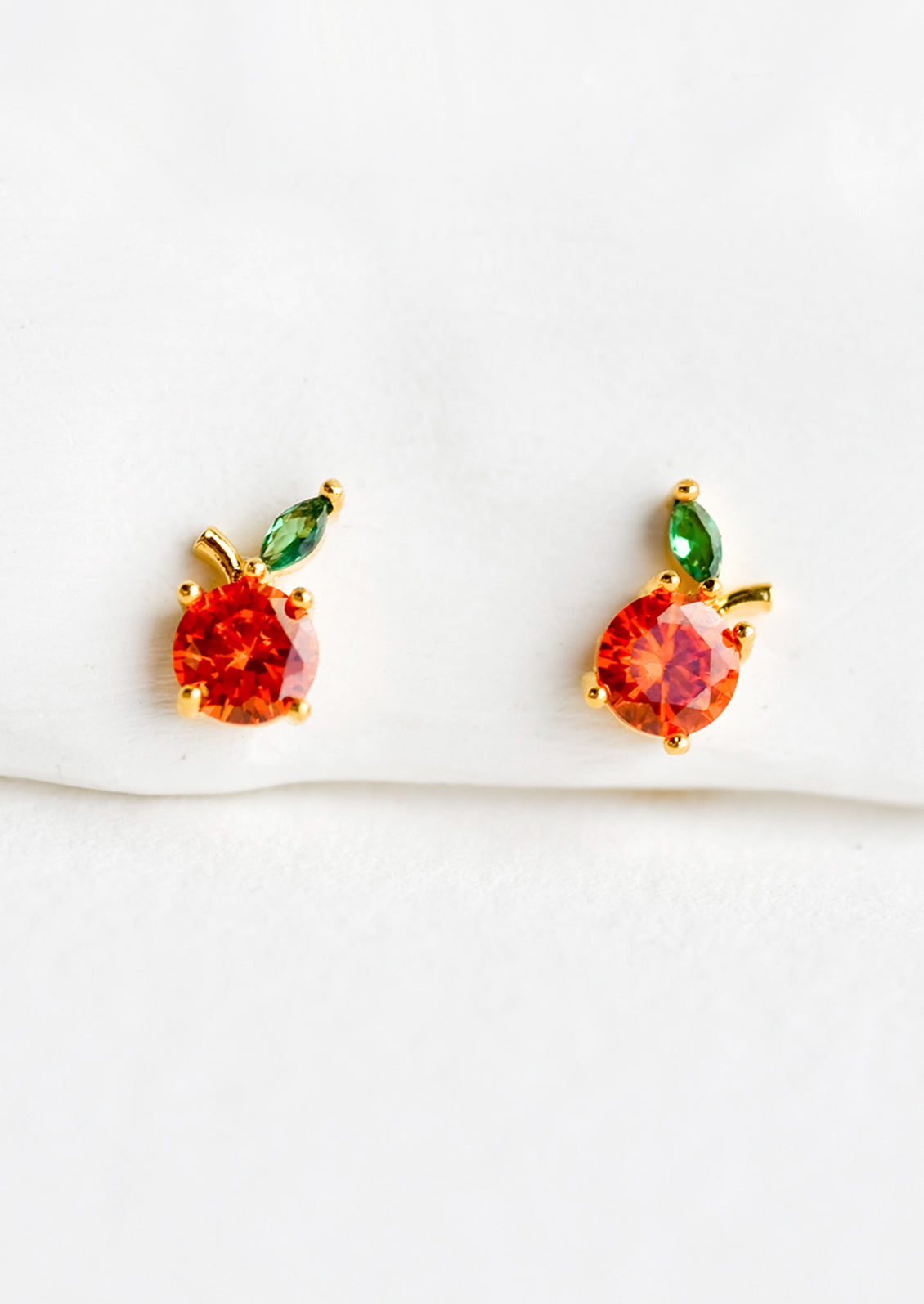 A pair of small crystal stud earrings in the shape of oranges.