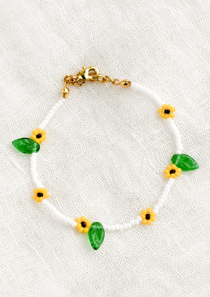 A white beaded bracelet with yellow beaded "sunflowers".