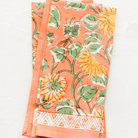 1: Pair of peach cotton napkins with yellow and green sunflower print.