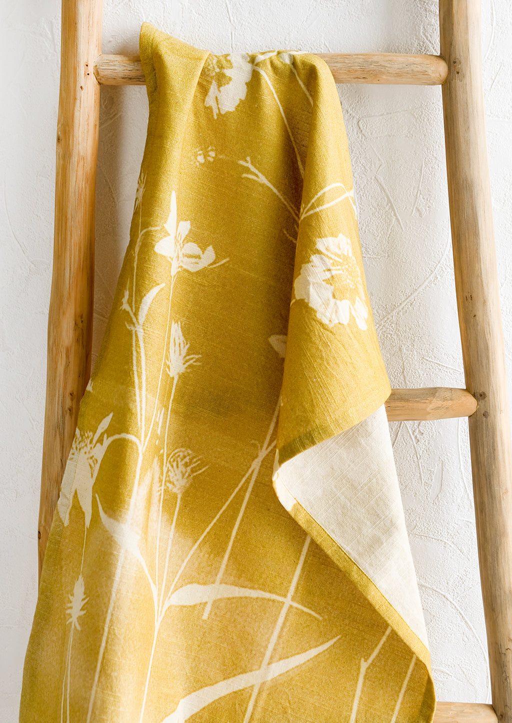 1: A yellow cotton tea towel with "bleached" look floral print.