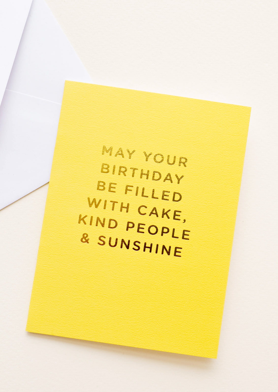 Yellow notecard with the text "May Your Birthday Be Filled With Cake, Kind People & Sunshine" in gold foil.