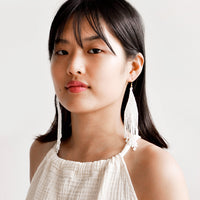 3: Model wears white beaded fringe earrings and white blouse.